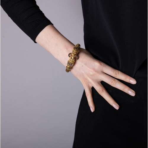 82 - LALAOUNIS: A GOLD AND GEM-SET BANGLE  Of woven foxtail linking, terminating in lion's head motifs at... 