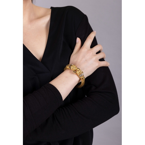 82 - LALAOUNIS: A GOLD AND GEM-SET BANGLE  Of woven foxtail linking, terminating in lion's head motifs at... 