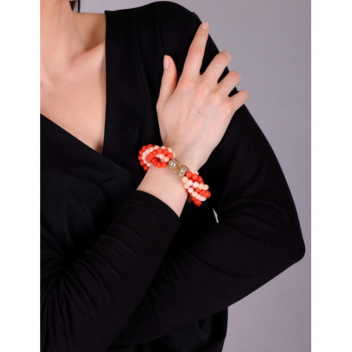 91 - A CORAL AND GOLD BRACELET, CIRCA 1970  Of torsade design, set with six strands of red and angel's sk... 