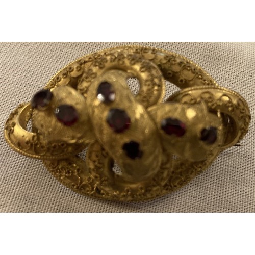 99 - Yellow metal brooch of entwined circles set with eight rubies.