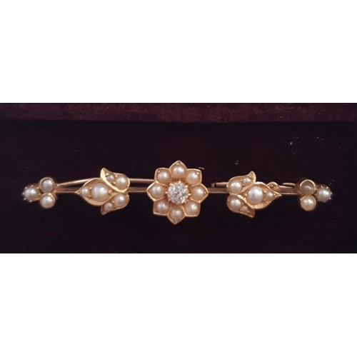 103 - An unmarked yellow metal bar brooch set with pearls in flower shaped form and one central diamond