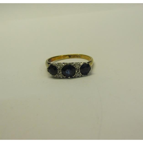 211 - An 18ct gold and platinum three stone ring, set with Sapphire and Diamonds.  Ring size L.