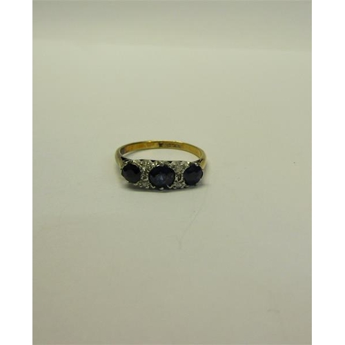 211 - An 18ct gold and platinum three stone ring, set with Sapphire and Diamonds.  Ring size L.