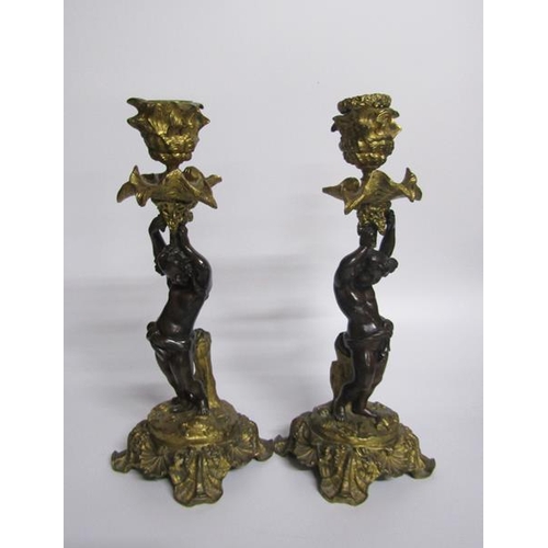 60 - A pair of late 19c gilt and patinated bronze candlesticks with putti columns supporting the socles a... 