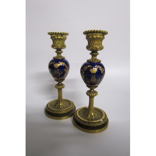 63 - A pair of late 19c ormolu and ceramic candlesticks, the ceramic knops with jewelled gilt wreath desi... 