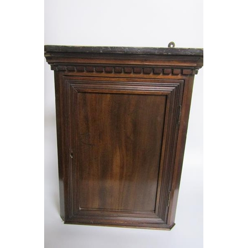 76A - A 19c mahogany hanging corner cupboard of small proportion with a shelved interior enclosed by a pan... 