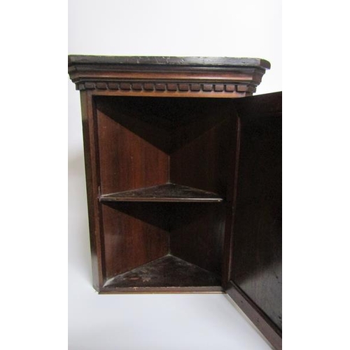 76A - A 19c mahogany hanging corner cupboard of small proportion with a shelved interior enclosed by a pan... 