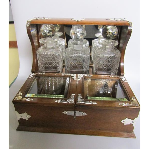 83 - A late 19c oak three bottle locking tantalus.  The tantalus has silver plated cut mounts and escutch... 