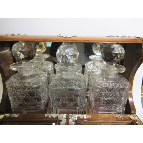 83 - A late 19c oak three bottle locking tantalus.  The tantalus has silver plated cut mounts and escutch... 