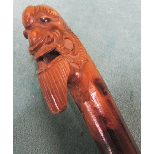 98 - An Oriental walking stick with carved mask handle.  94cms l.