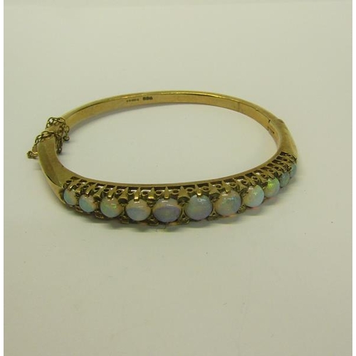 202 - A 9ct gold bangle set with eleven graduated opals - 23g overall.