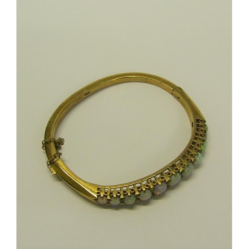 202 - A 9ct gold bangle set with eleven graduated opals - 23g overall.