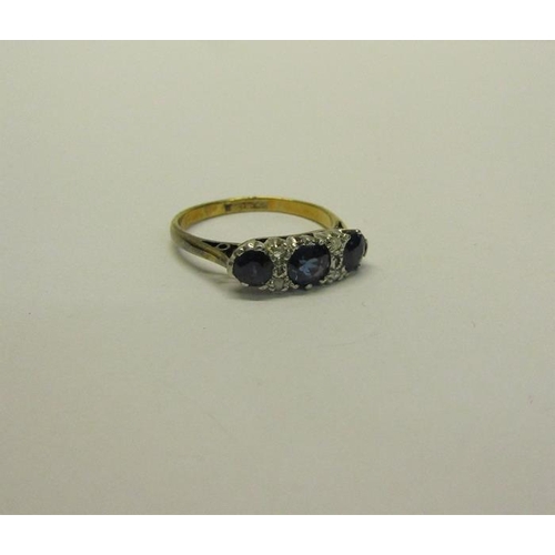 211 - An 18ct gold and platinum three stone ring, set with Sapphire and Diamonds.  Ring size L.