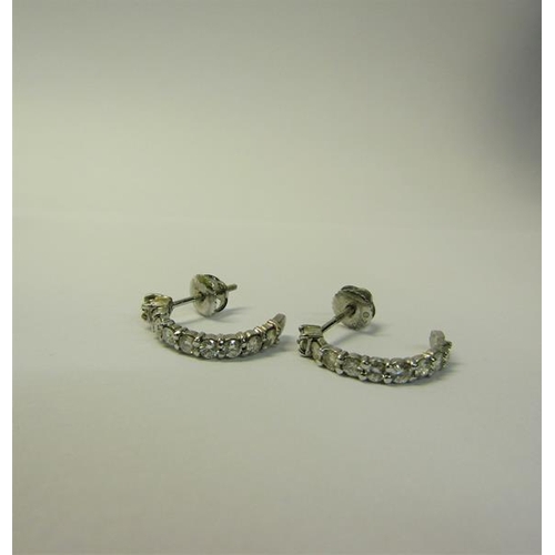 173 - A pair of 18ct white gold and Diamond set half hoop earrings.