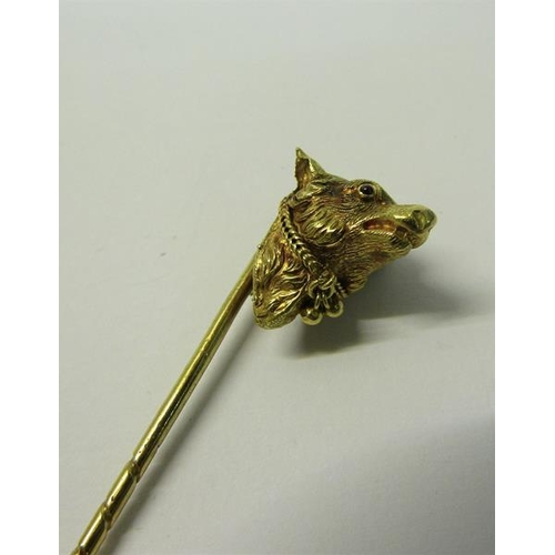 183 - An Edwardian gold stick pin with a dog's head terminal, having ruby eyes, collar with bell.  9.5cms ... 