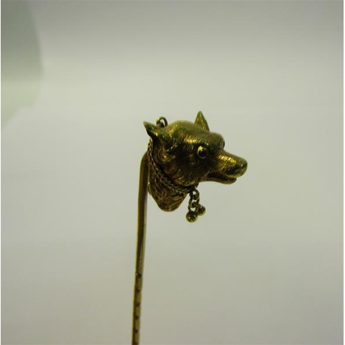 183 - An Edwardian gold stick pin with a dog's head terminal, having ruby eyes, collar with bell.  9.5cms ... 