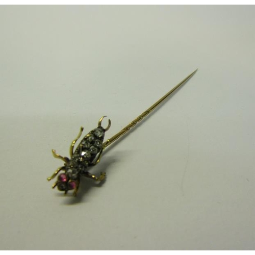 185 - A gold stick pin with Diamond and Ruby set insect terminal.  6cms l.