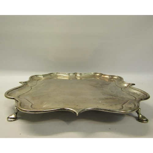 302 - An Edwardian silver salver of quatrefoil form with raised shape border supported on four hoofed feet... 