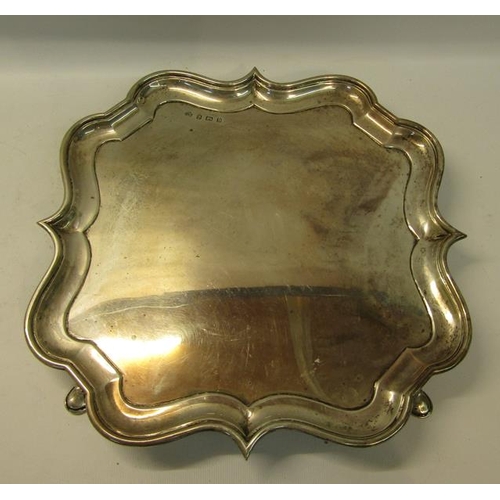 302 - An Edwardian silver salver of quatrefoil form with raised shape border supported on four hoofed feet... 