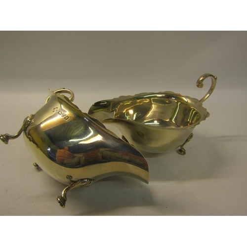 253 - A pair of silver sauceboats with shaped top rims and open scrolling handles and on three hoof feet. ... 