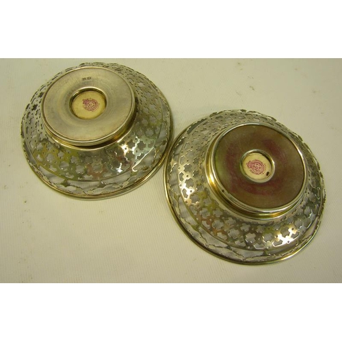 237 - A pair of circular silver bowls, pierced and with James Stinton Royal Worcester bases, both decorate... 