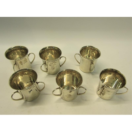 239 - A set of six silver tyg shaped tots, each with three handles being of cylindrical form with a spread... 