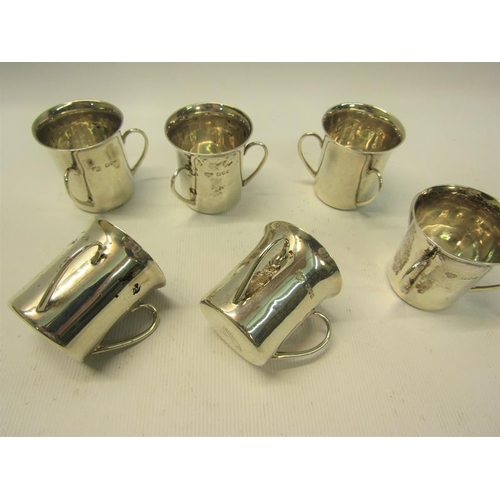 239 - A set of six silver tyg shaped tots, each with three handles being of cylindrical form with a spread... 