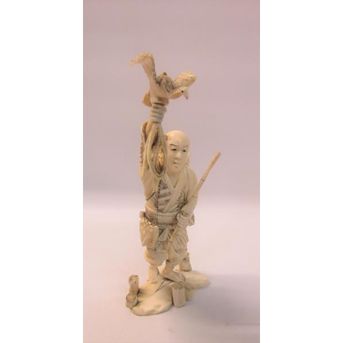 114 - A Japanese Meiji period carved ivory figure of a fisherman holding his Cormorant aloft in his right ... 