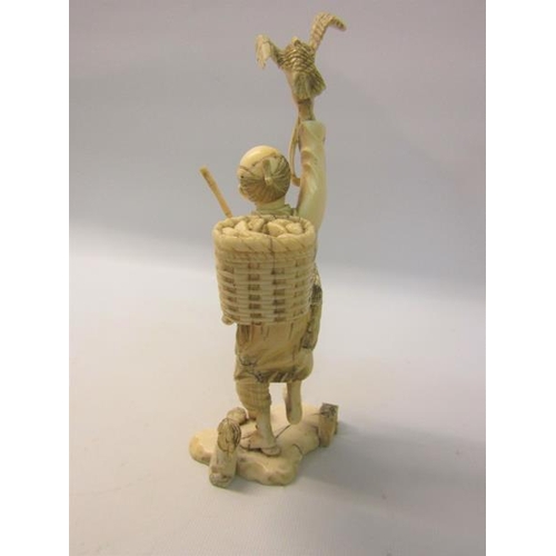 114 - A Japanese Meiji period carved ivory figure of a fisherman holding his Cormorant aloft in his right ... 