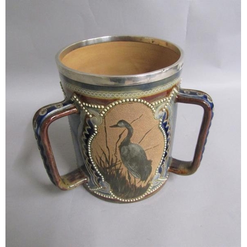 396 - A 19c Doulton Lambeth Florence Barlow three handled tyg with silver rim, with three pate sur pate pa... 