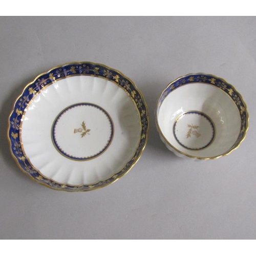 373 - A Worcester fluted tea bowl and saucer with blue and gilt border, gilt Thistle reserved in base.  Cr... 