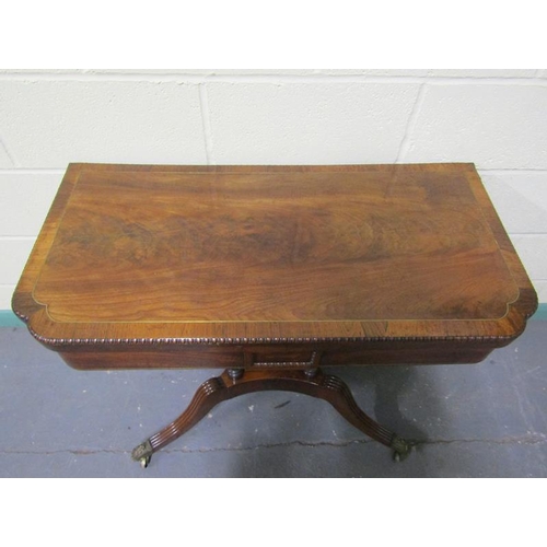 545 - A Regency rosewood fold over card table with brass rail inlay raised on a stretcher frame with ring ... 