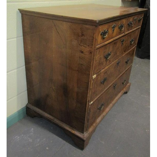 546 - An 18c figured walnut chest of two short and three long graduated drawers.  The top with wide cross ... 