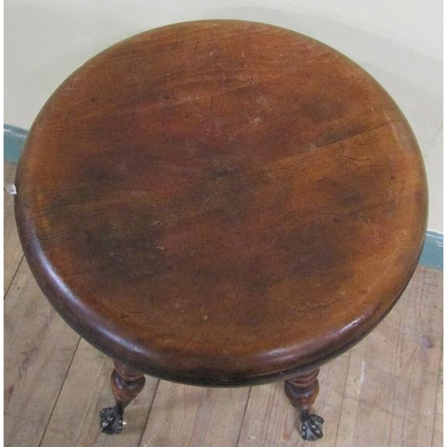 562 - A Victorian oak revolving piano stool supported on four ring turned legs with claw and glass ball fe... 