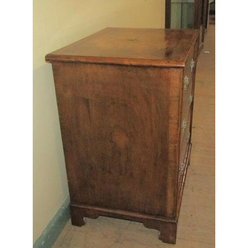 575 - A mid Georgian style figured walnut veneered small chest of three long drawers.  The top and drawer ... 