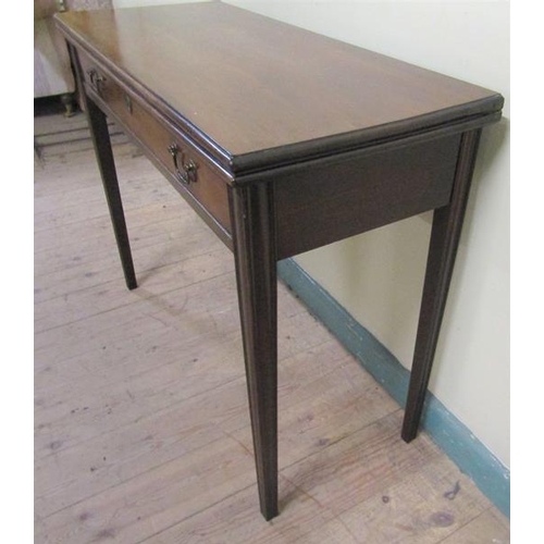 586 - A late Georgian mahogany fold over table of rectangular form with moulded edge having one long friez... 