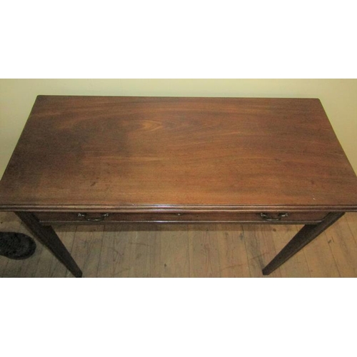 586 - A late Georgian mahogany fold over table of rectangular form with moulded edge having one long friez... 