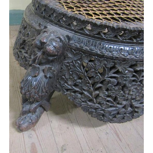 615 - Early 19c Indian ebony low chair the base of circular form, profusely carved apron.  The legs are ca... 