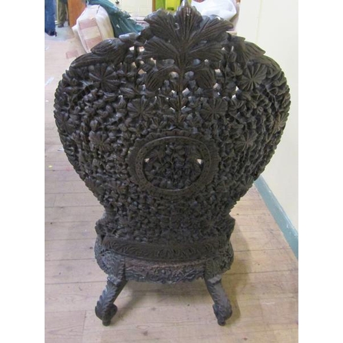 615 - Early 19c Indian ebony low chair the base of circular form, profusely carved apron.  The legs are ca... 