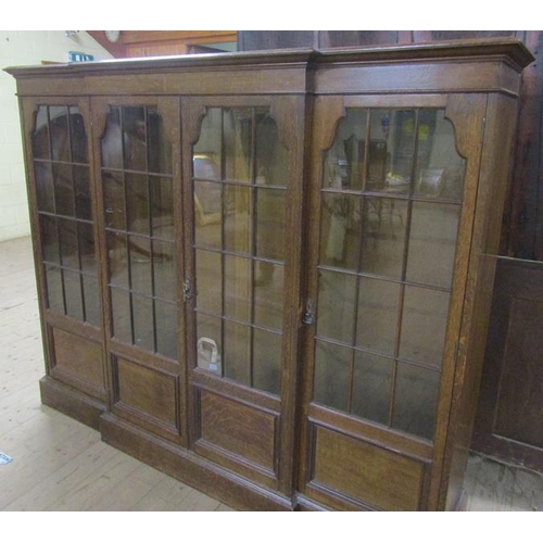 577 - A late 19c/early 20c oak breakfront standing bookcase with fitted shelves and enclosed by glazed doo... 