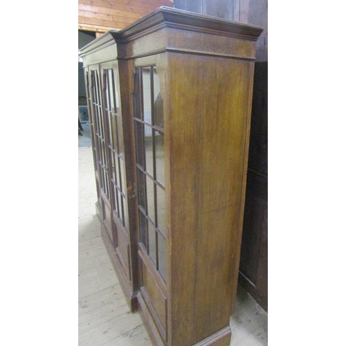 577 - A late 19c/early 20c oak breakfront standing bookcase with fitted shelves and enclosed by glazed doo... 