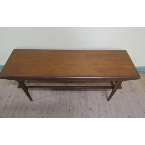 623 - A 1970s teak low table of rectangular form with a caned under tier shelf, supported on straight tape... 