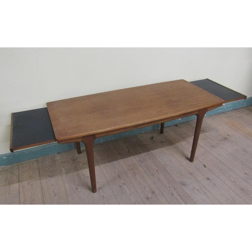 632 - A 1970's teak low table of rectangular shaped form with two pull out end shelves and supported on ci... 