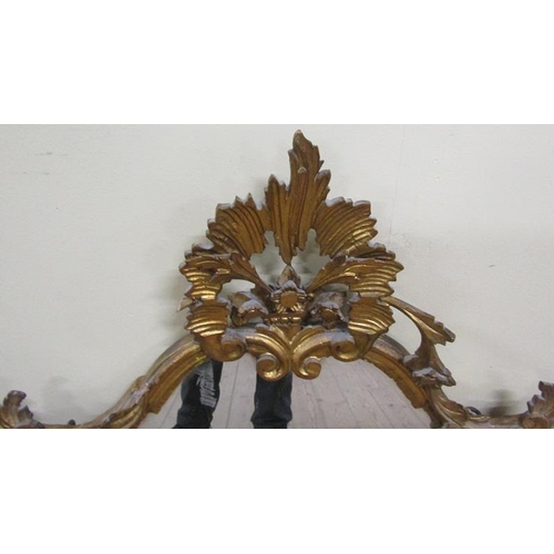 592 - A mid Georgian style gilt wooden stucco wall mirror with a rising leaf and scroll pediment within a ... 