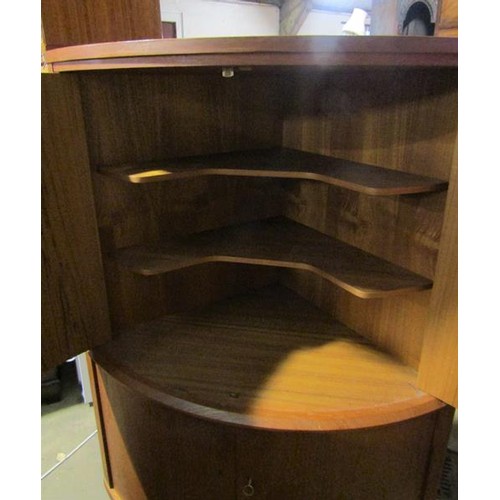 634 - A 1970's teak standing bow front corner cupboard with upper and lower shelves enclosed by hinged doo... 