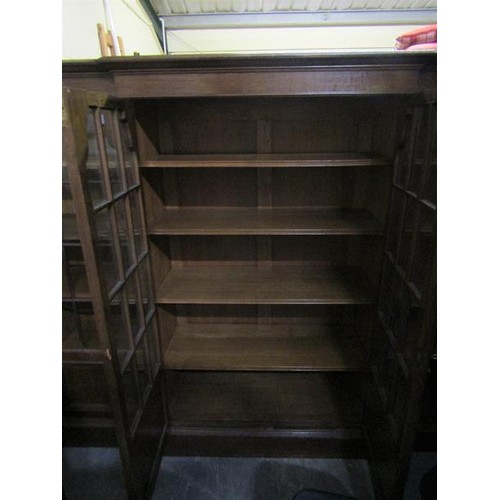 577 - A late 19c/early 20c oak breakfront standing bookcase with fitted shelves and enclosed by glazed doo... 