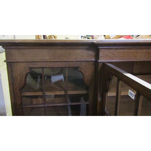 577 - A late 19c/early 20c oak breakfront standing bookcase with fitted shelves and enclosed by glazed doo... 