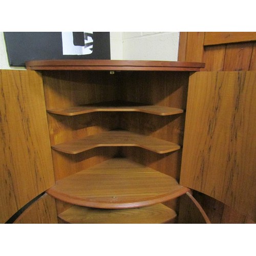 634 - A 1970's teak standing bow front corner cupboard with upper and lower shelves enclosed by hinged doo... 