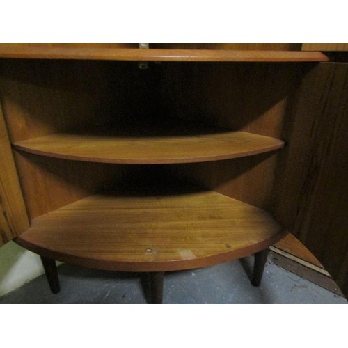 634 - A 1970's teak standing bow front corner cupboard with upper and lower shelves enclosed by hinged doo... 