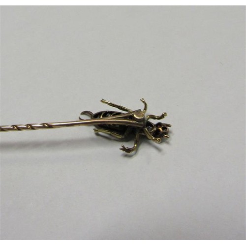 185 - A gold stick pin with Diamond and Ruby set insect terminal.  6cms l.